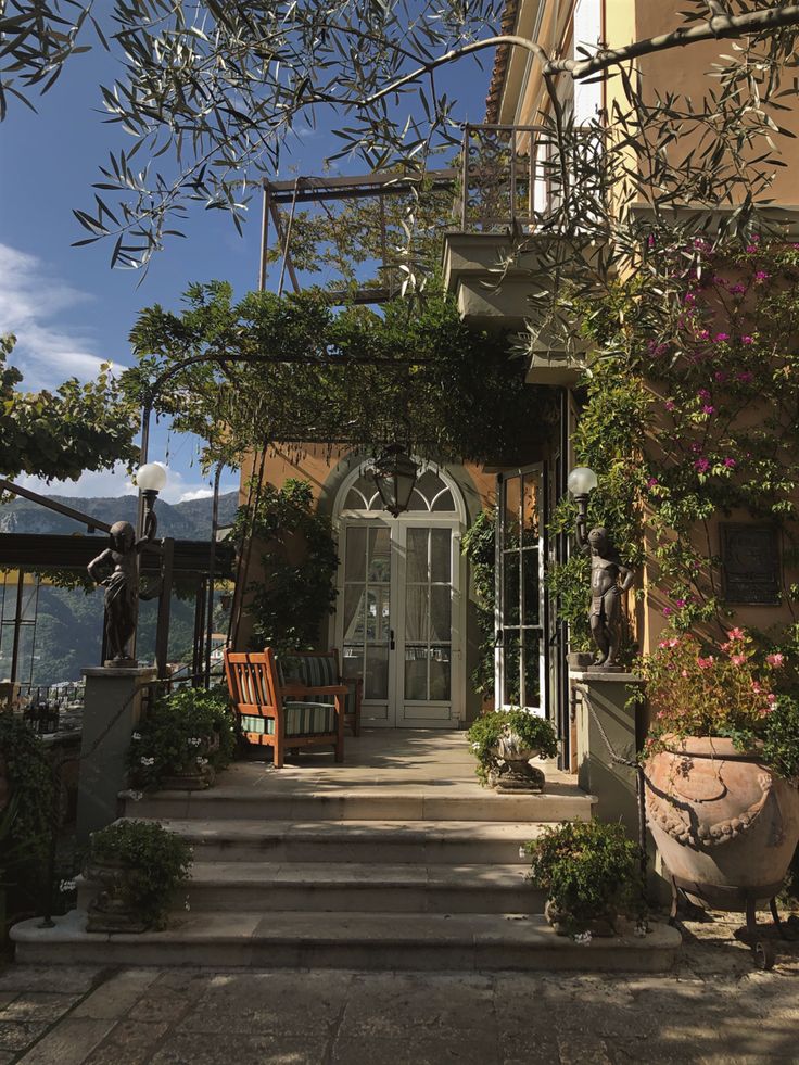 an outside view of a house with lots of plants on the front porch and stairs leading up to it