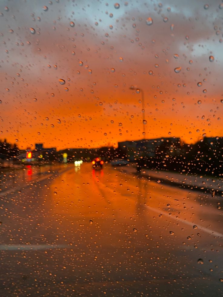 rain drops on the windshield of a car at sunset