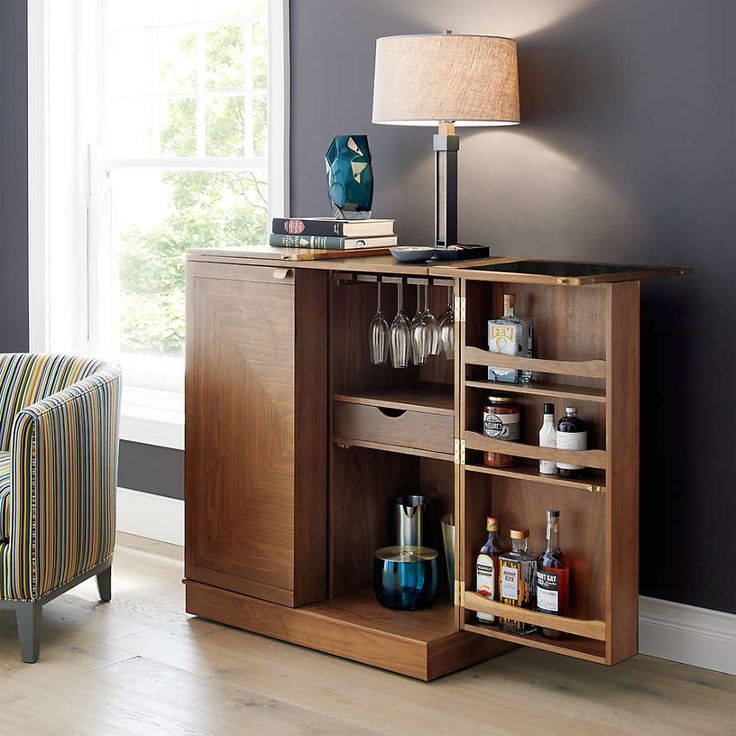 a room with a chair, table and shelves in it that have liquor glasses on them