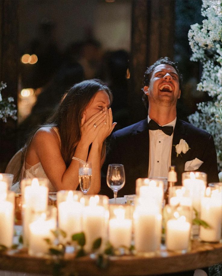 a man and woman are sitting at a table with candles in front of them on their wedding day