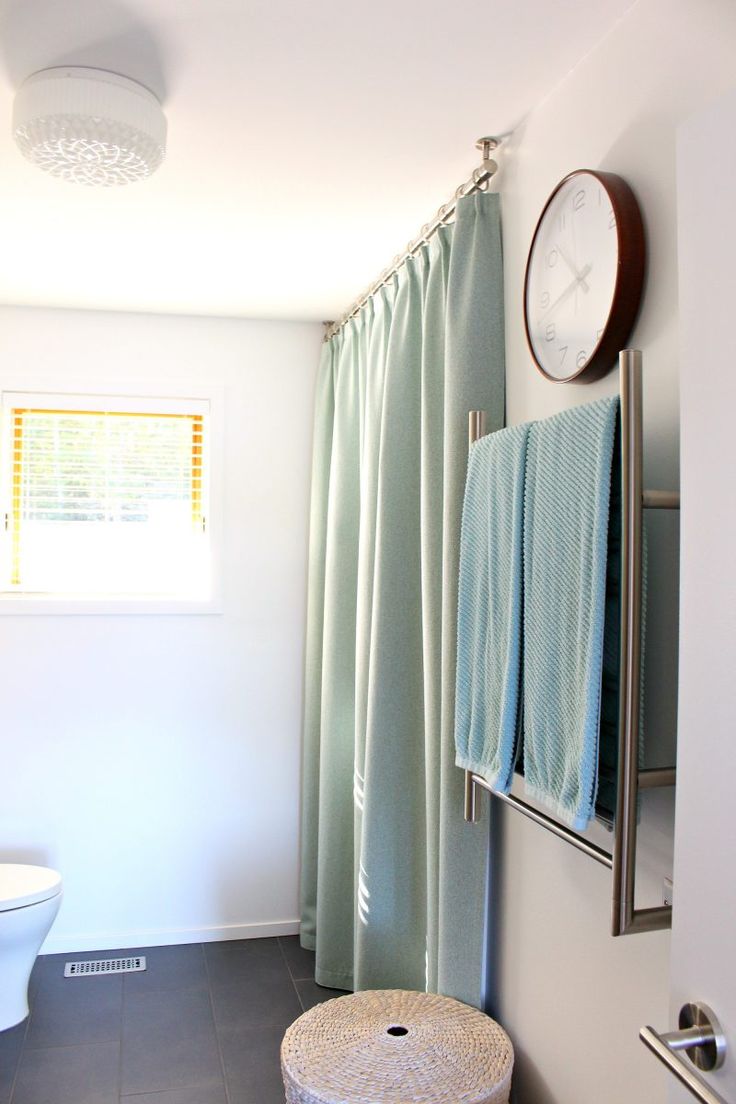 a white toilet sitting next to a shower in a bathroom under a clock on the wall