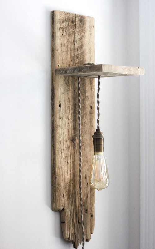 a light that is on the side of a wall next to a wooden plank and some string