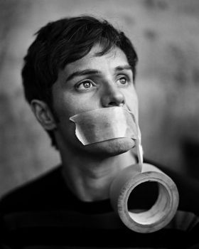 a man with duct tape on his mouth holding a roll of toilet paper in front of his face