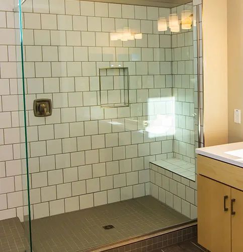 a bathroom with a walk in shower next to a white sink and counter top under a mirror