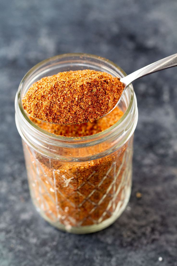 a jar filled with spices on top of a counter next to a spoon and fork