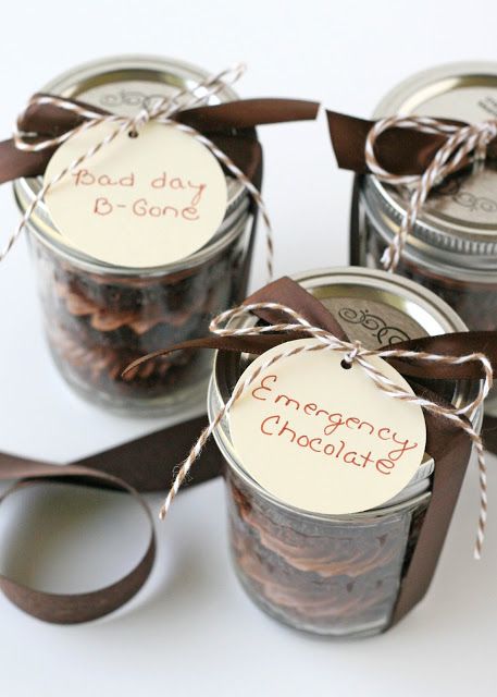 four jars filled with chocolate covered cookies on top of a white table next to scissors