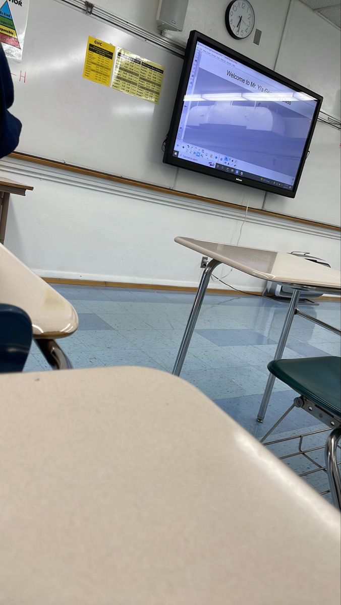 a classroom with desks, chairs and a flat screen tv