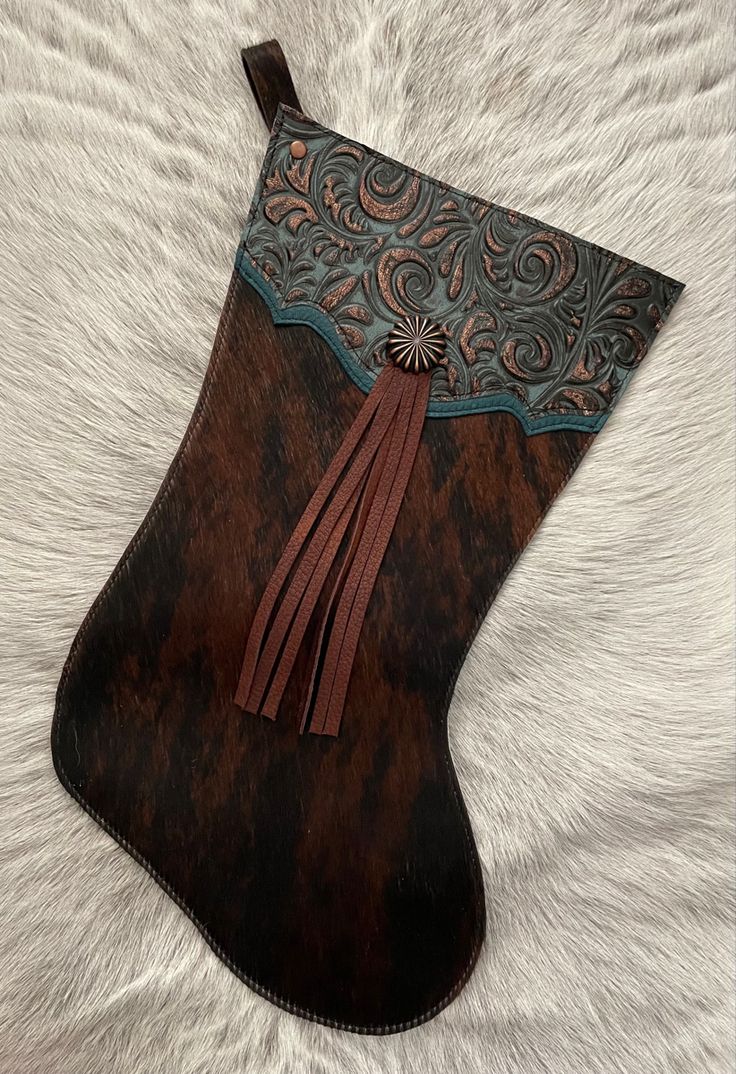 a brown leather stocking with tassels on it sitting on a white fur surface