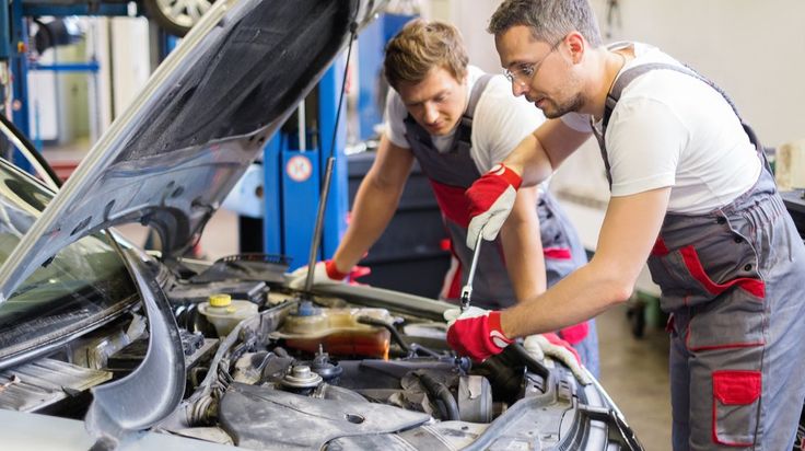 two mechanics working on a car in a garage