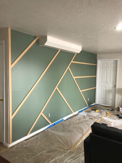 a room that has been painted green with gold lines on the wall, and is being worked on