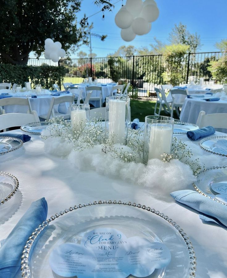 the table is set with blue and white linens, candles, and napkins