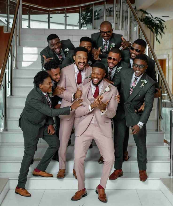 a group of men in suits and ties posing for a photo on the stairs with their hands together