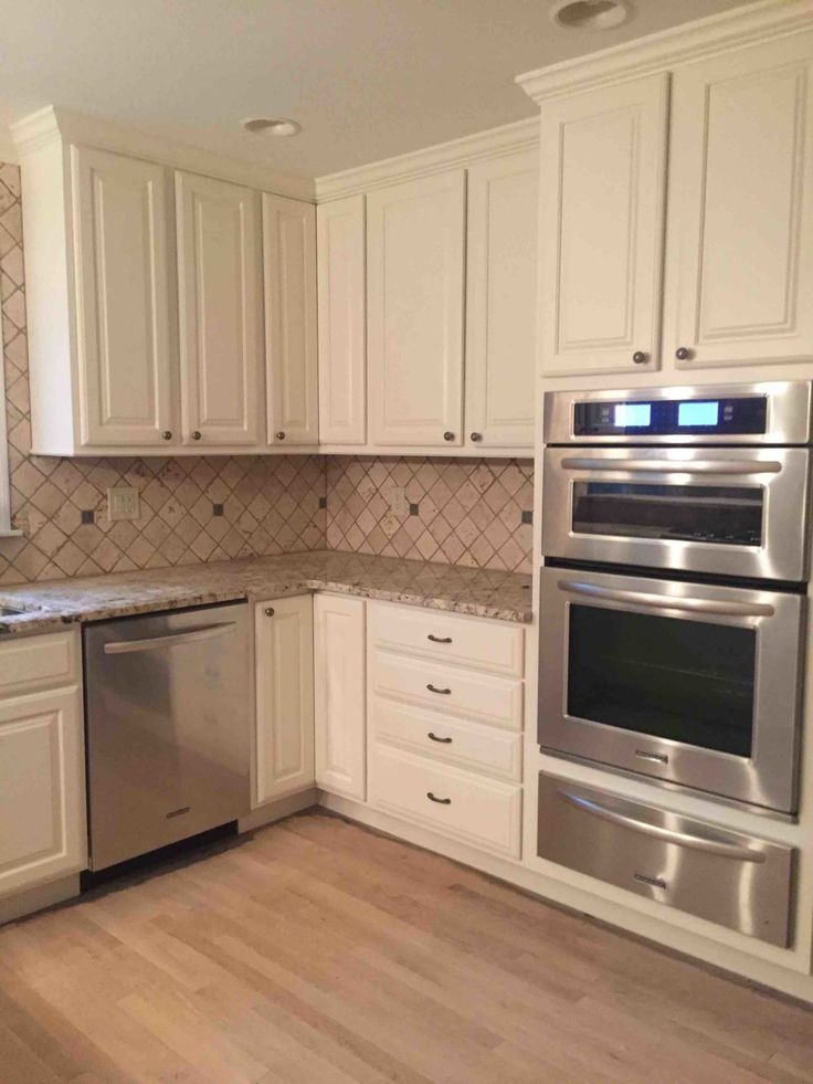 an empty kitchen with white cabinets and stainless steel appliances in the middle of the room