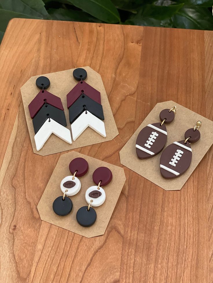 three pairs of earrings on top of a wooden table