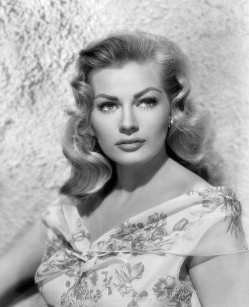 an old black and white photo of a woman wearing a dress with flowers on it