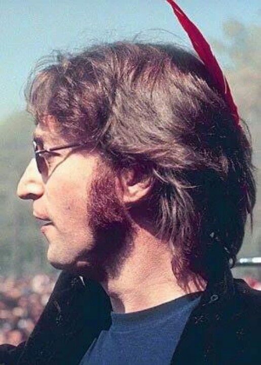 a man with long hair wearing a red bandana on his head and looking off into the distance