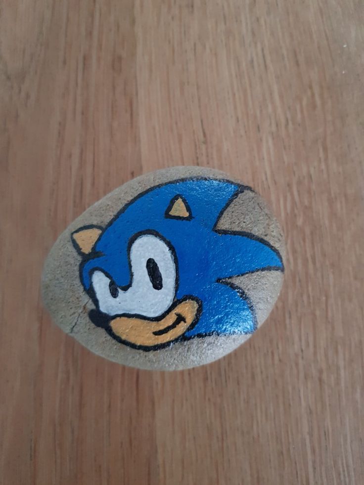 a rock painted to look like sonic the hedgehog is on a table with wood