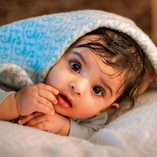 a baby laying on top of a bed under a blanket