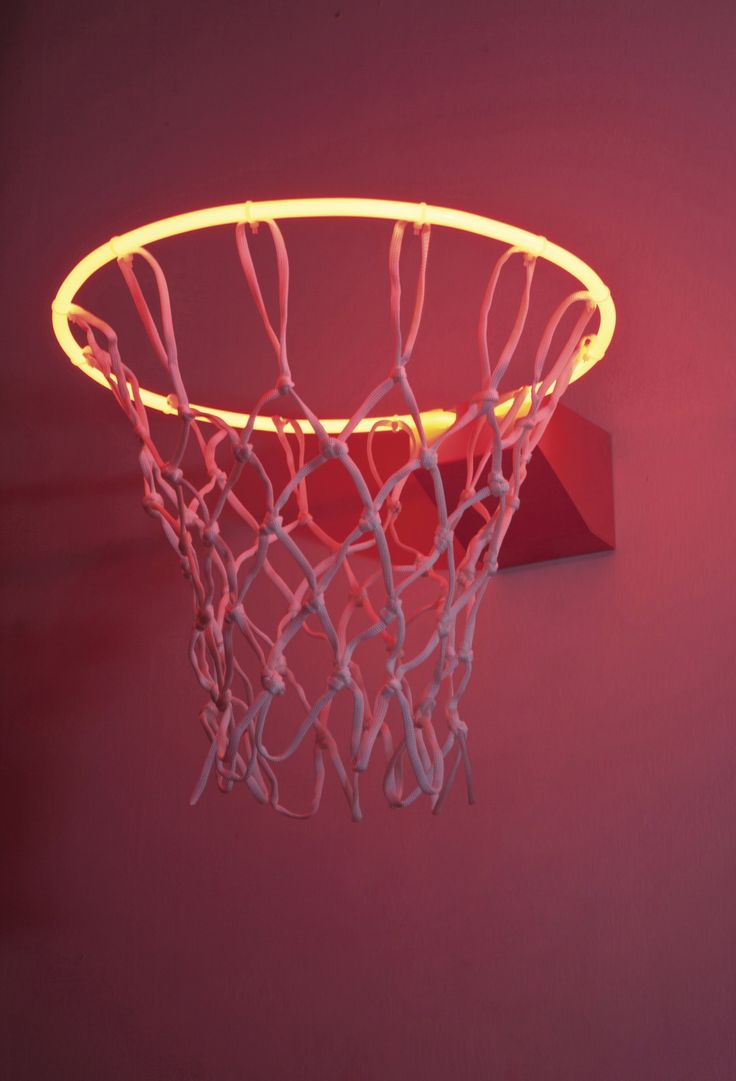 a basketball hoop that is lit up with neon lights on the side and in front of a red wall