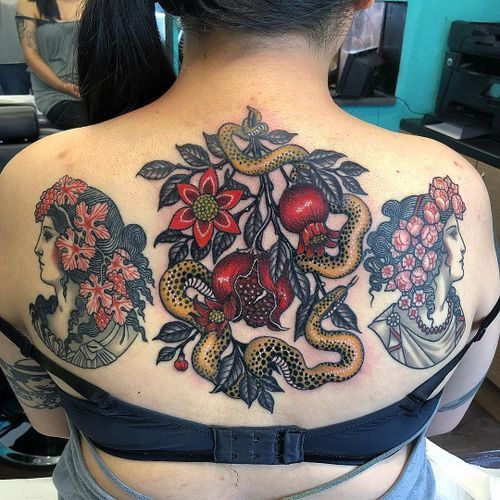 the back of a woman's shoulder with tattoos on her body and two snakes