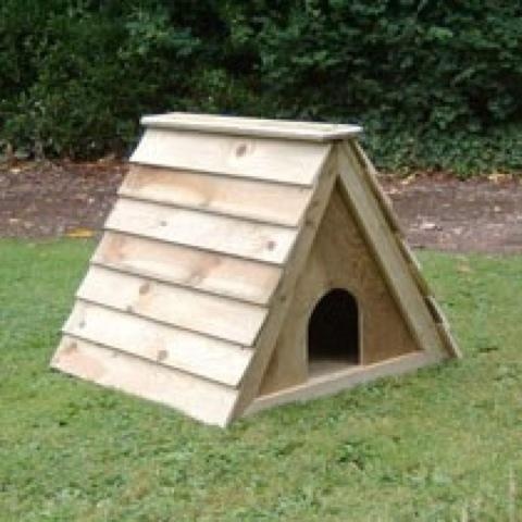 a wooden dog house sitting in the grass