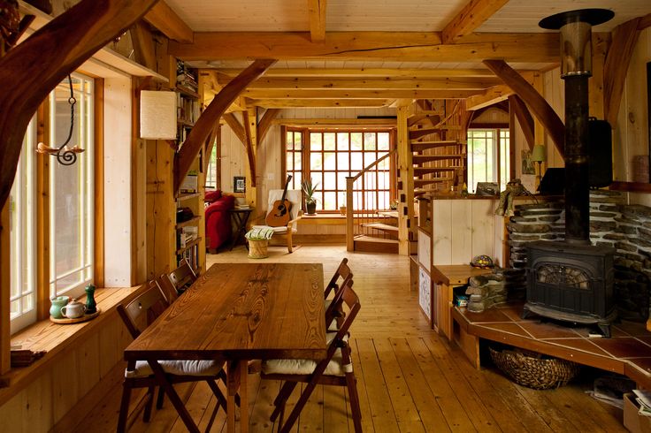 a room with wood floors and wooden beams on the ceiling is filled with chairs, tables, and an open fire place