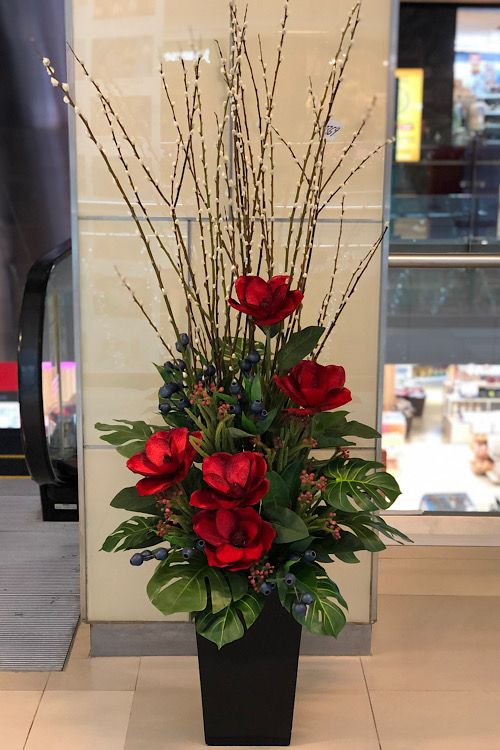 a vase filled with red flowers on top of a counter