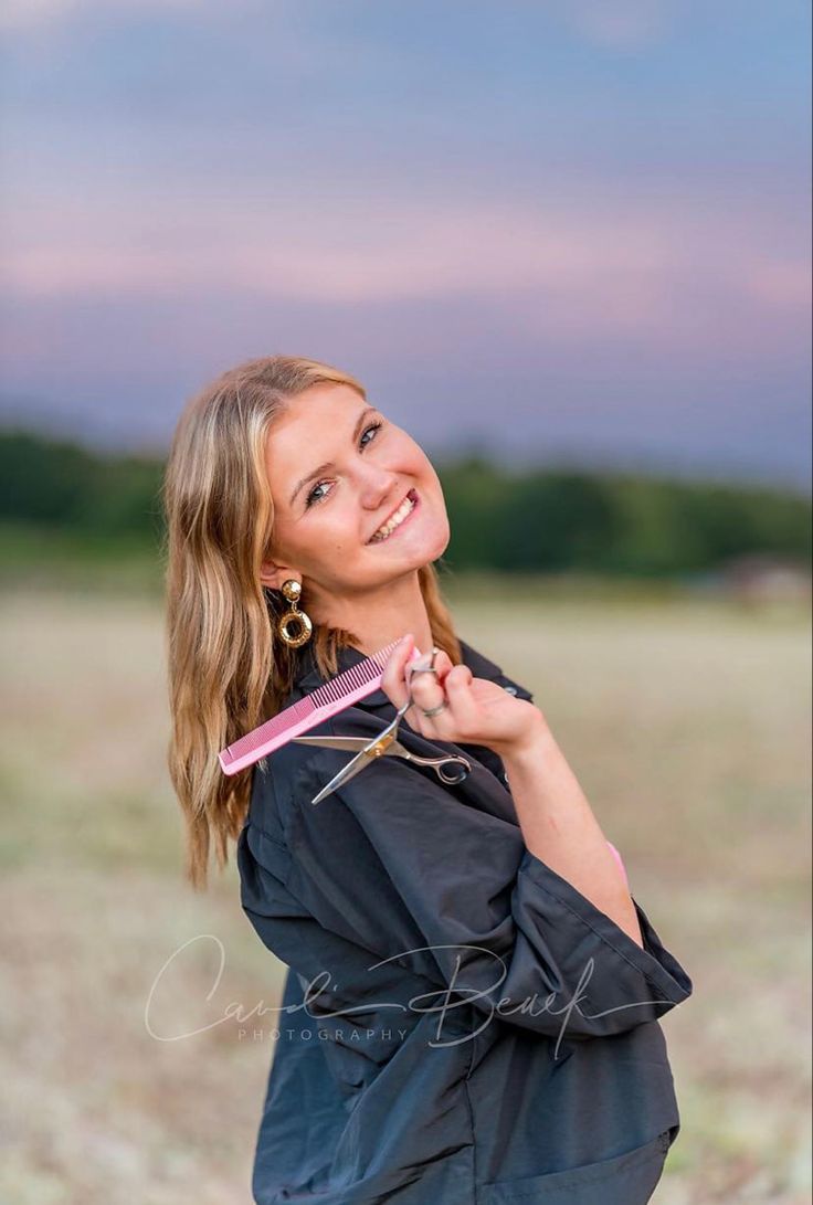 a woman holding a pink toothbrush in her right hand and smiling at the camera