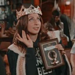 a woman wearing a tiara holding an award in front of her face and looking at the camera