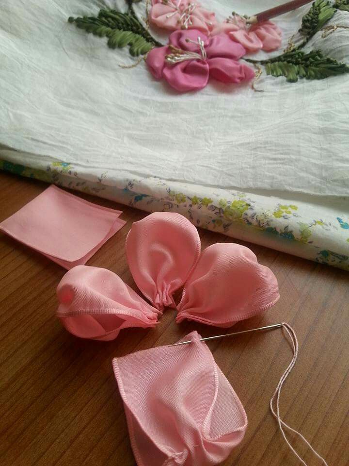 three pink bows are sitting on a table next to a white sheet and some flowers