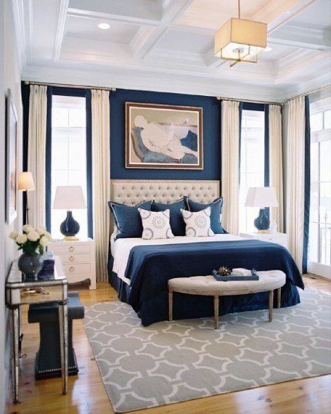 a bedroom with blue walls and white bedding, rugs on hardwood flooring