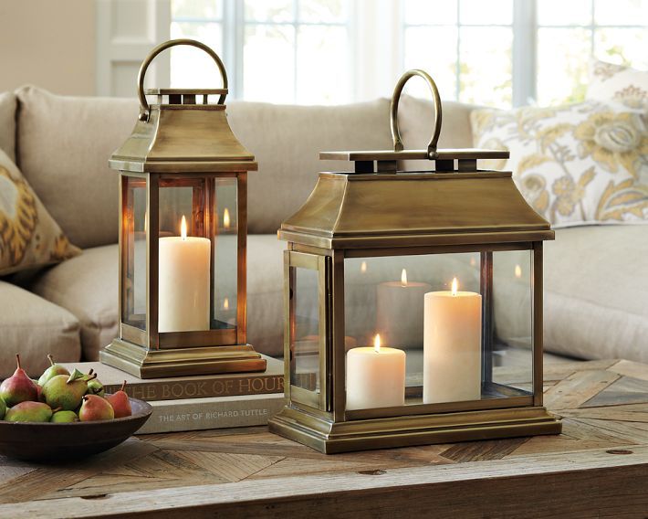 two lit candles sitting on top of a wooden table next to a bowl of fruit