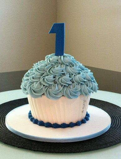 a blue frosted cupcake with the number one on it sitting on a plate