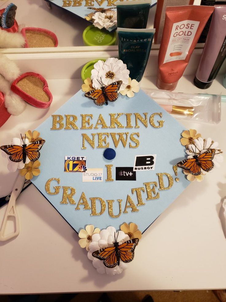 a blue graduation cap that says breaking news i graduated with butterflies and flowers on it