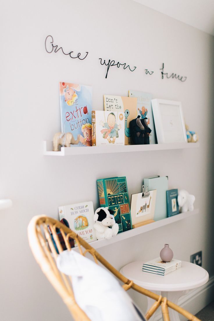 a white chair sitting in front of a window next to a shelf filled with books