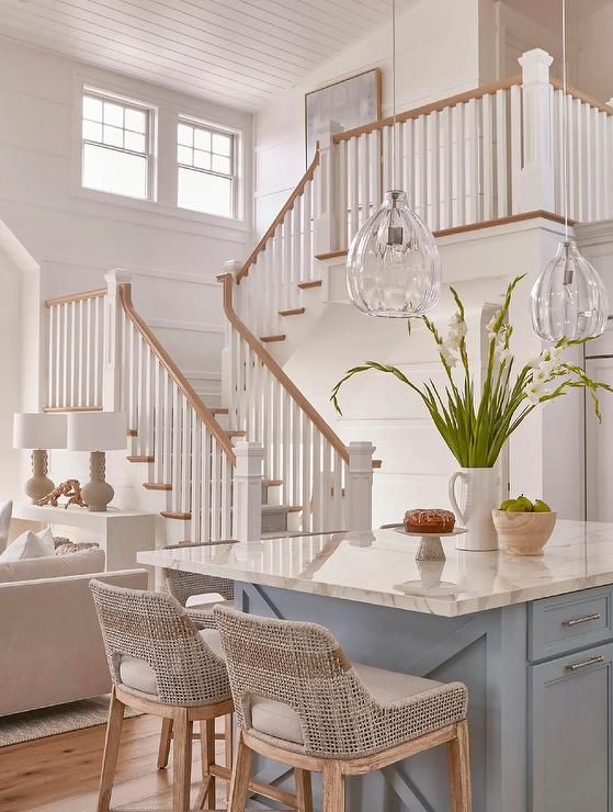 a kitchen island with stools next to it in front of a staircase leading up to the second floor