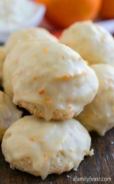 orange cookies with icing sitting on top of a wooden table next to an orange