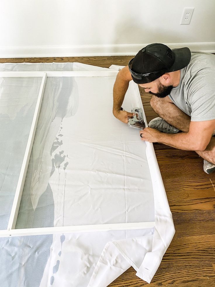 a man laying on the floor with a paintbrush and tape around his body while painting