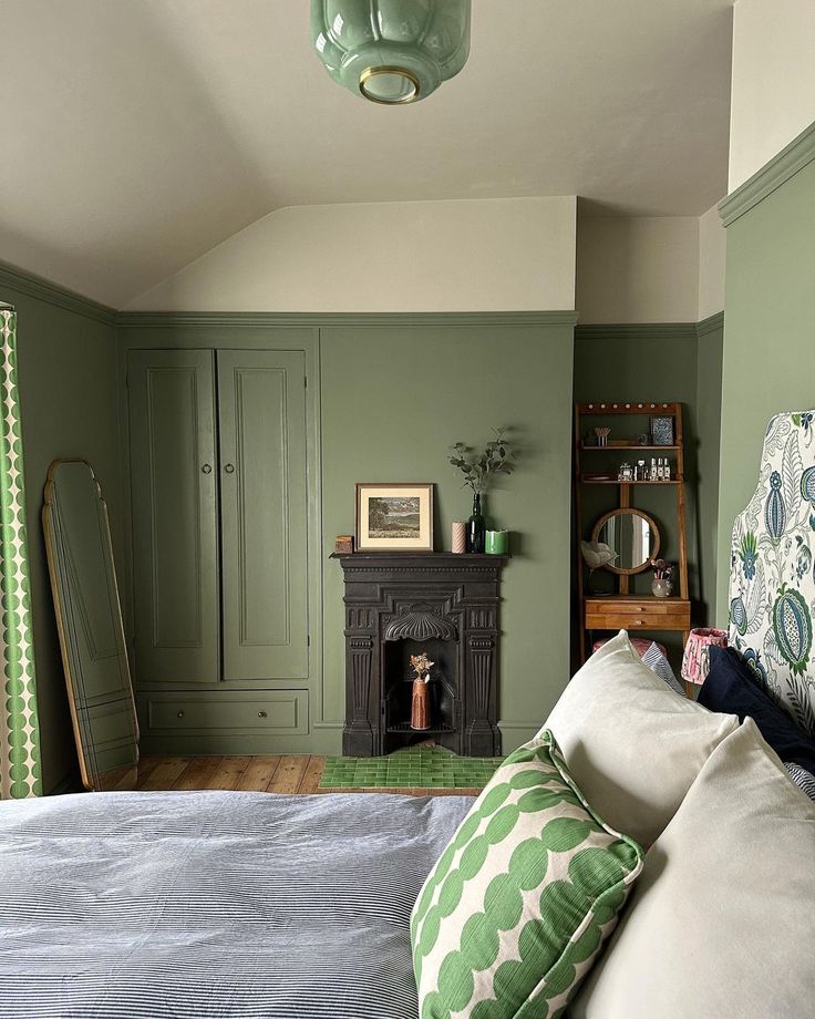 a bedroom with green walls and white bedding in the corner, along with a fireplace