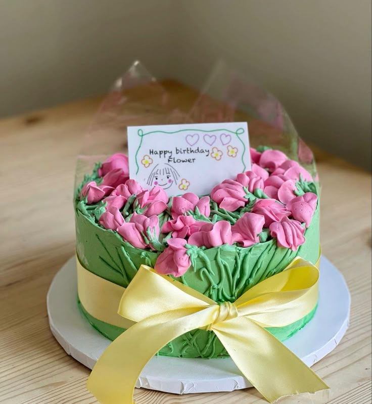 a birthday cake decorated with pink flowers and green leaves