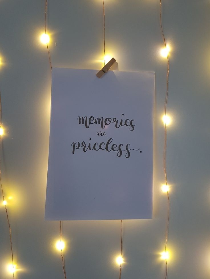 a piece of paper that says memories are priceless hanging on a string of lights