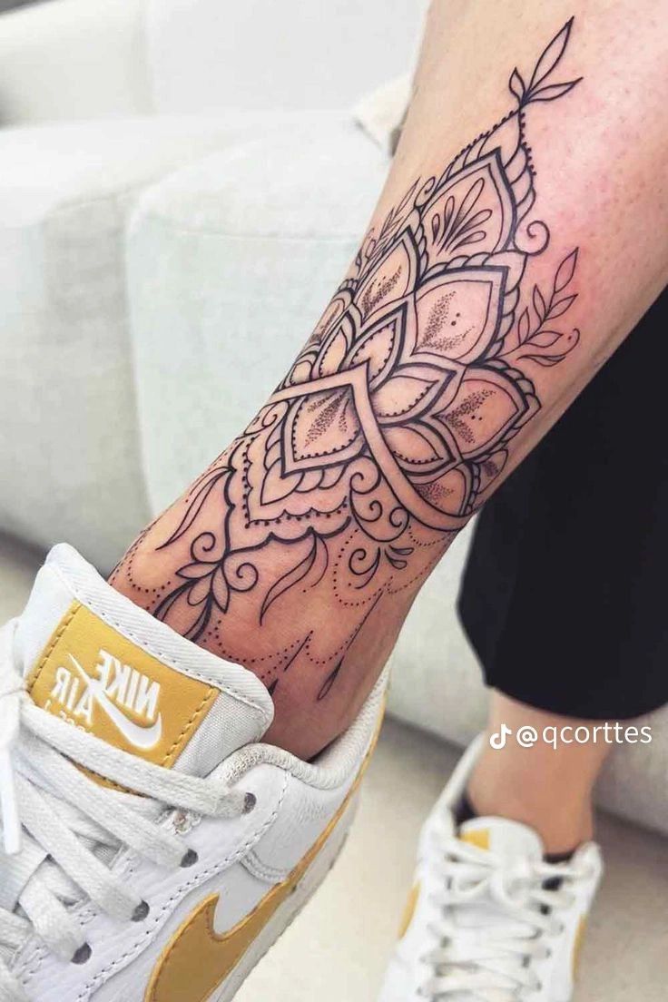 a woman's foot with a tattoo on it and a nike air force sneakers