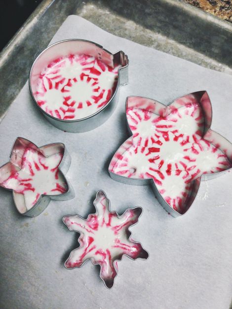 three red and white cookies sitting on top of a cookie sheet next to each other