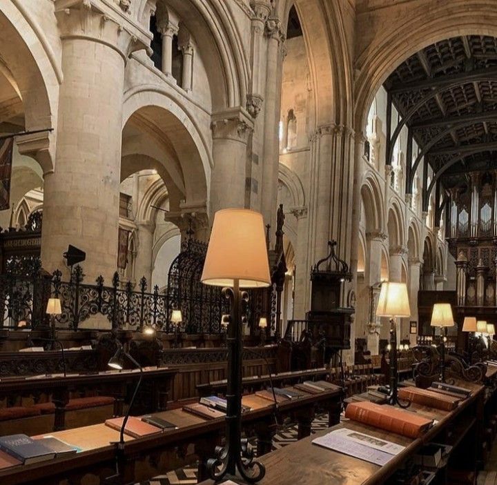 the interior of a large cathedral with many tables and lamps on each side of it