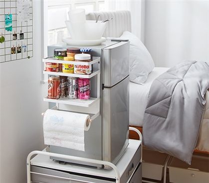 a small refrigerator in the corner of a bedroom next to a bed with white sheets on it