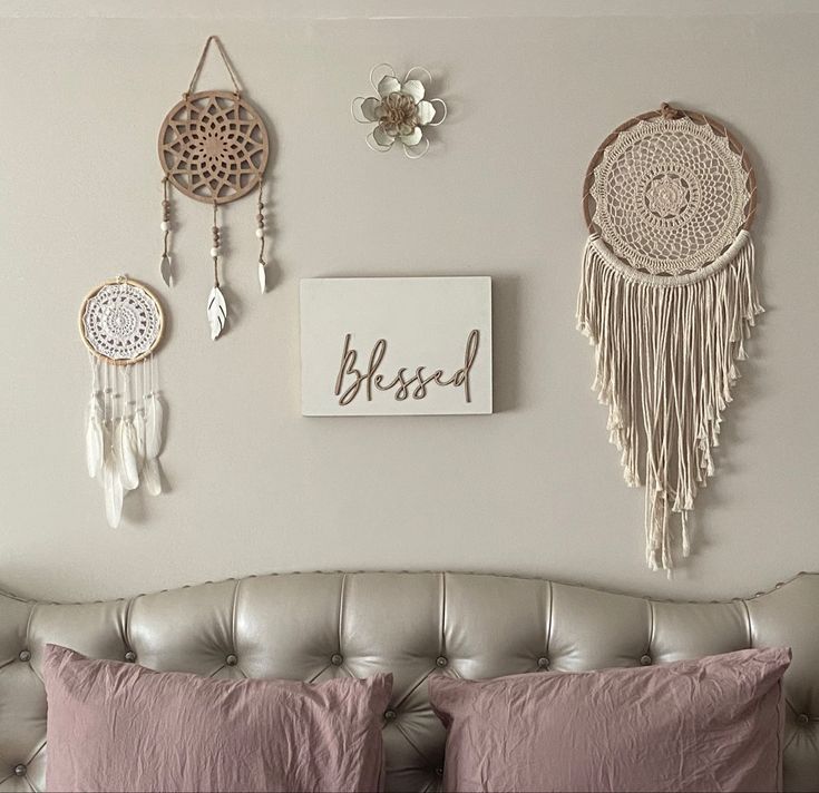 there are three dream catchers hanging on the wall next to a couch with pink pillows