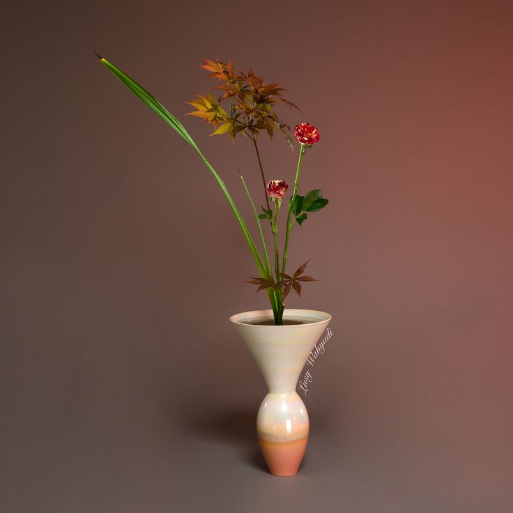 there is a vase with flowers in it on the table next to a brown wall