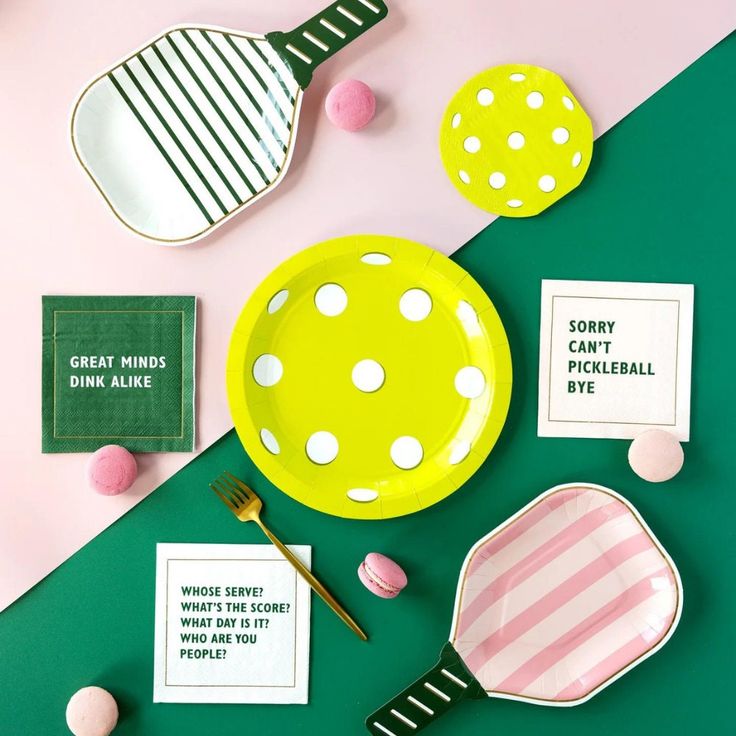 plates, spoons and candy on a table with pink and green decor around them