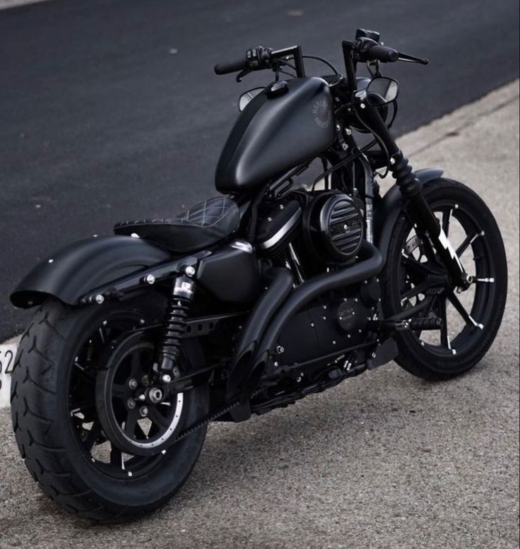 a black motorcycle parked on the street next to a curb with no one around it