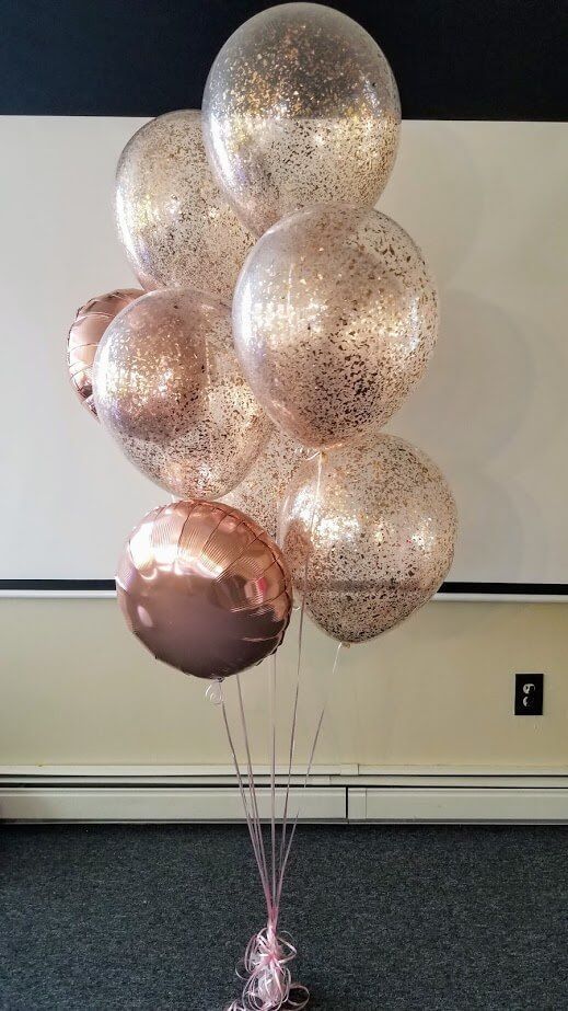 a bunch of balloons that are sitting on the ground in front of a white wall